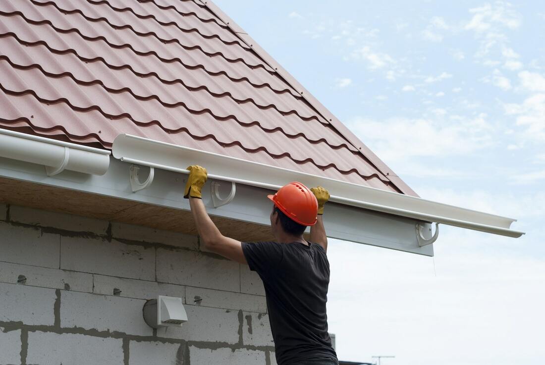 Specialist completing gutter repair on a Bergen County - NJ home while adjusting pitch near a downspout