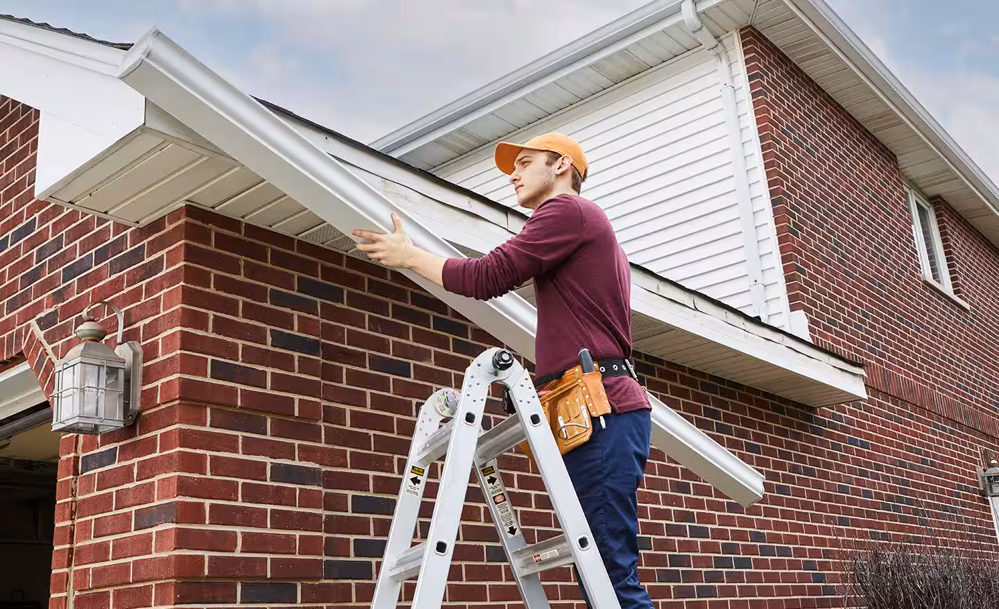 Specialist completing gutter repair on a Bergen County - NJ home while adjusting pitch near a downspout